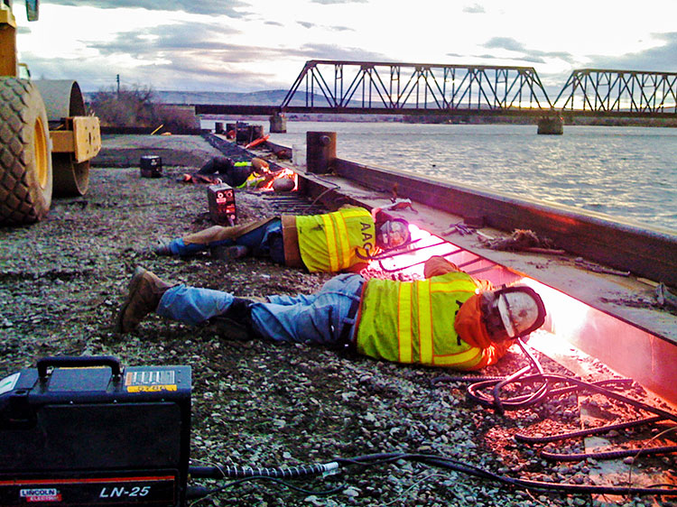 Welders working laying down